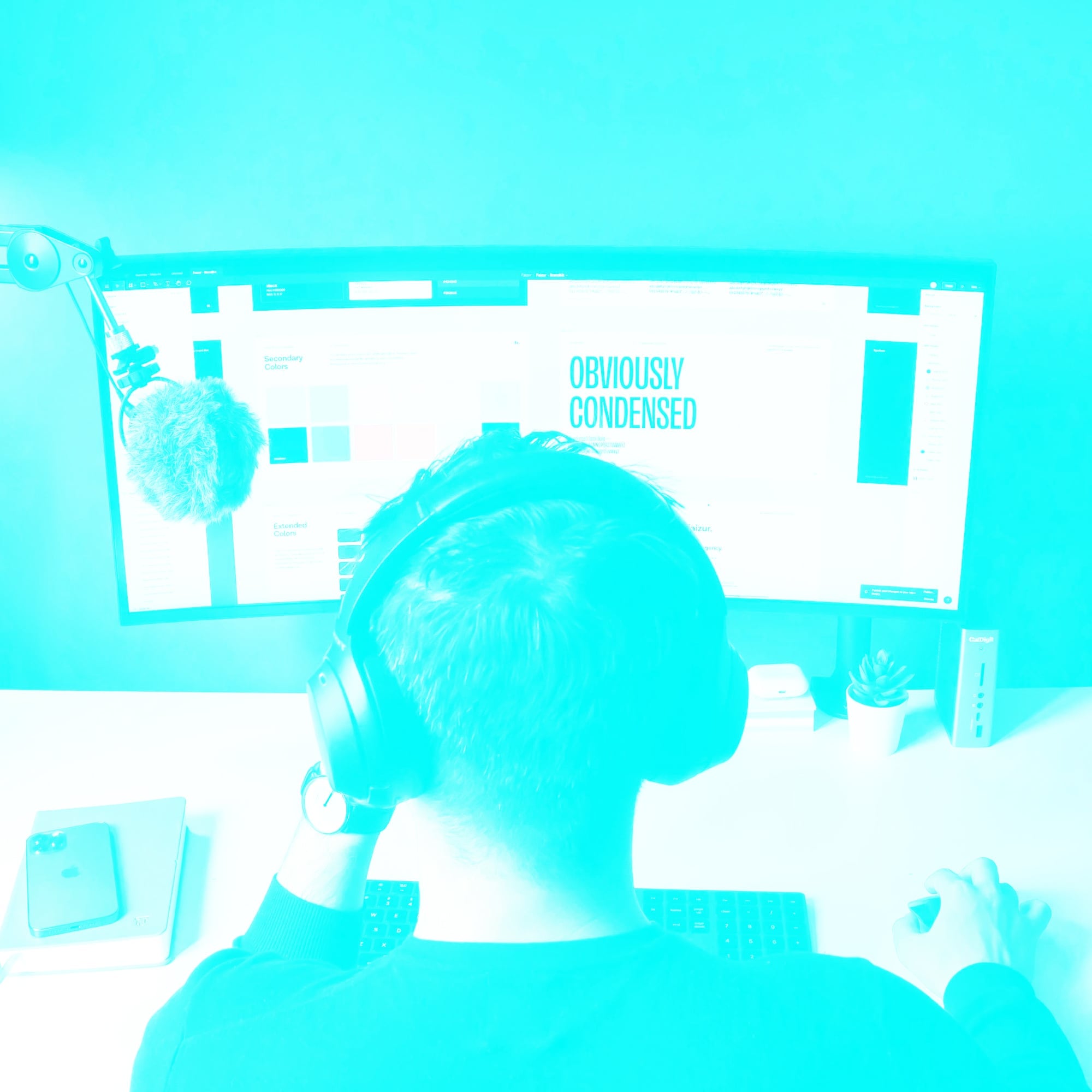 designer with headphones at dual monitor brand style guide teal