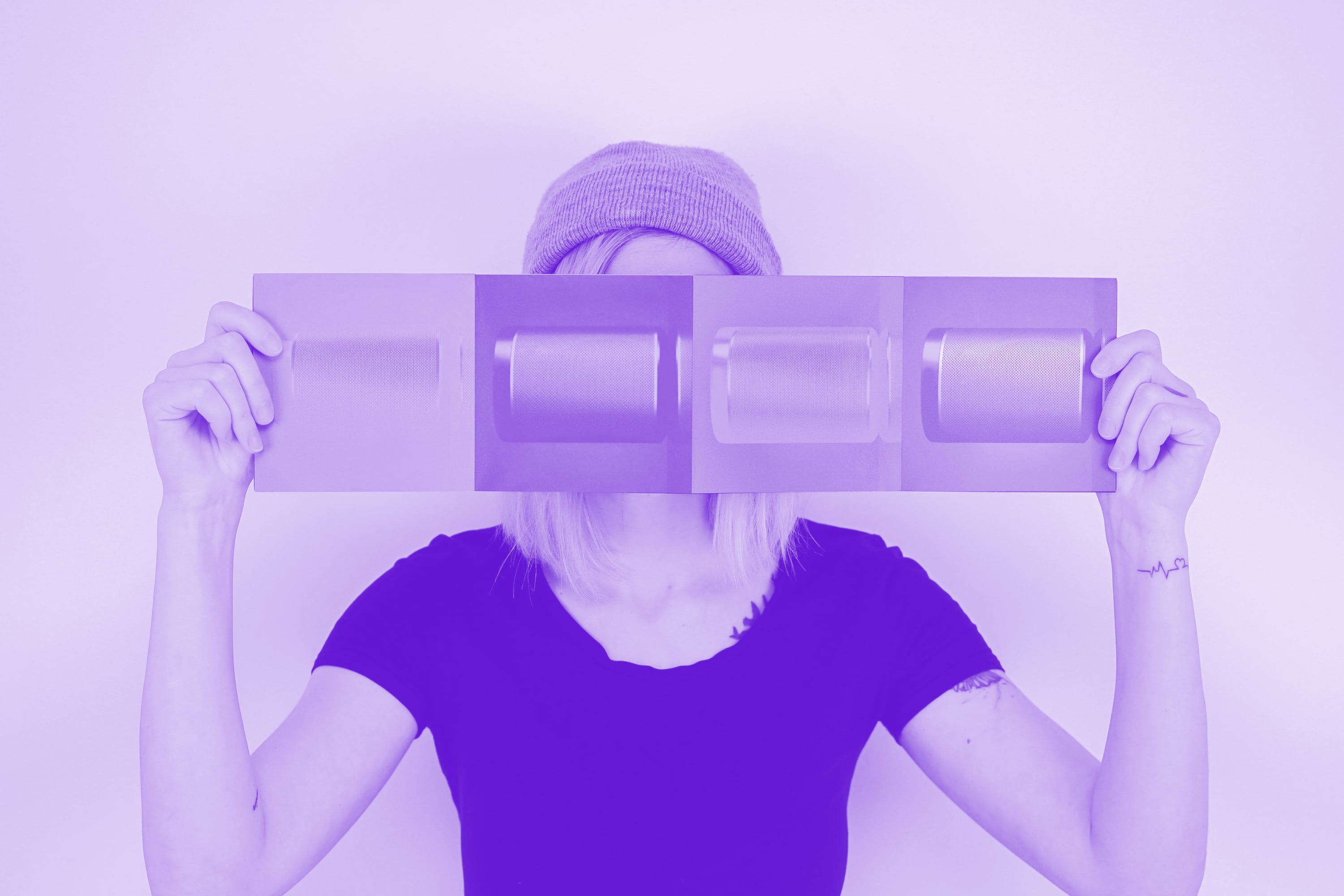 woman in beanie hat holding printed brochure panel purple toned