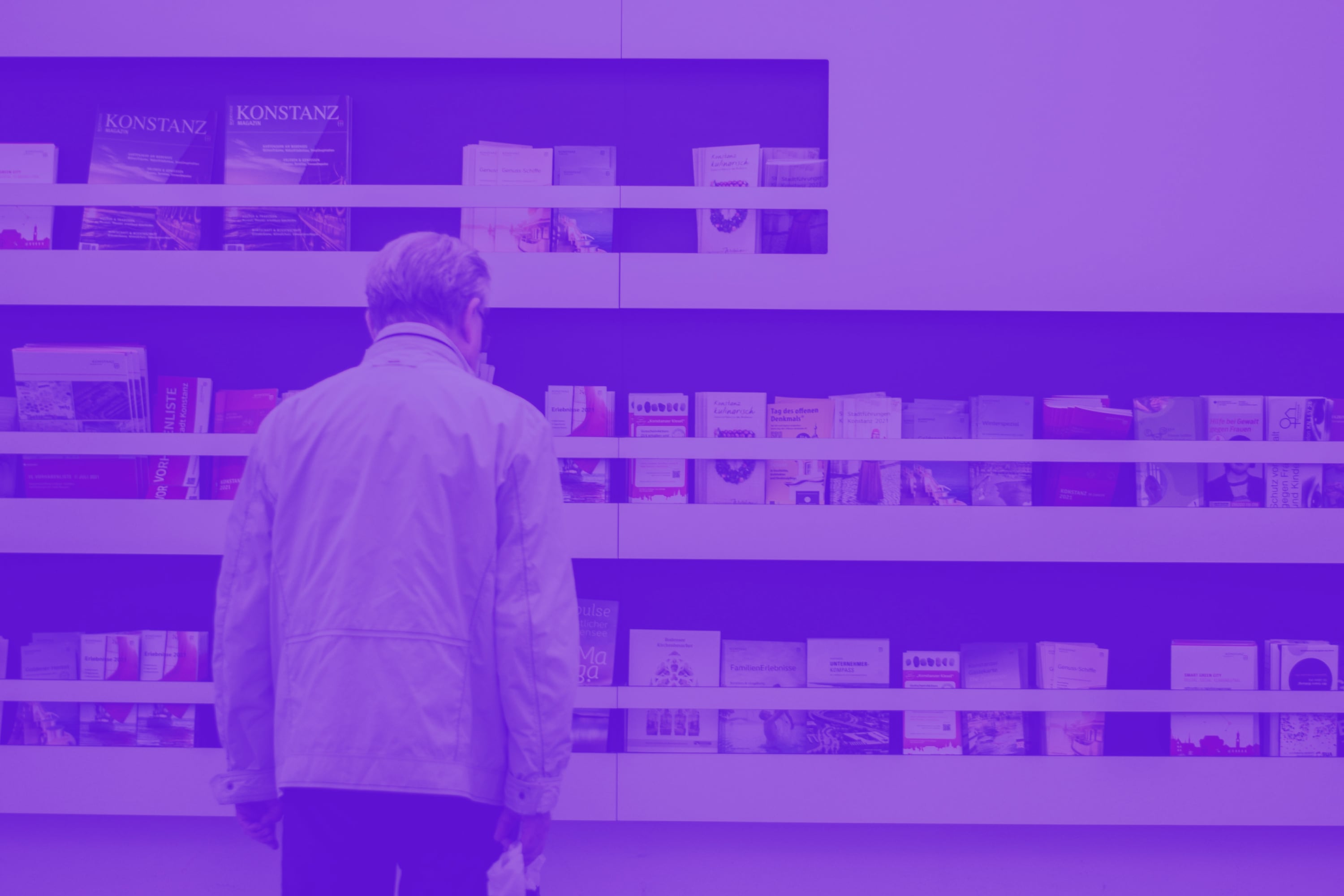 man browsing brochures on display shelves exhibition purple toned