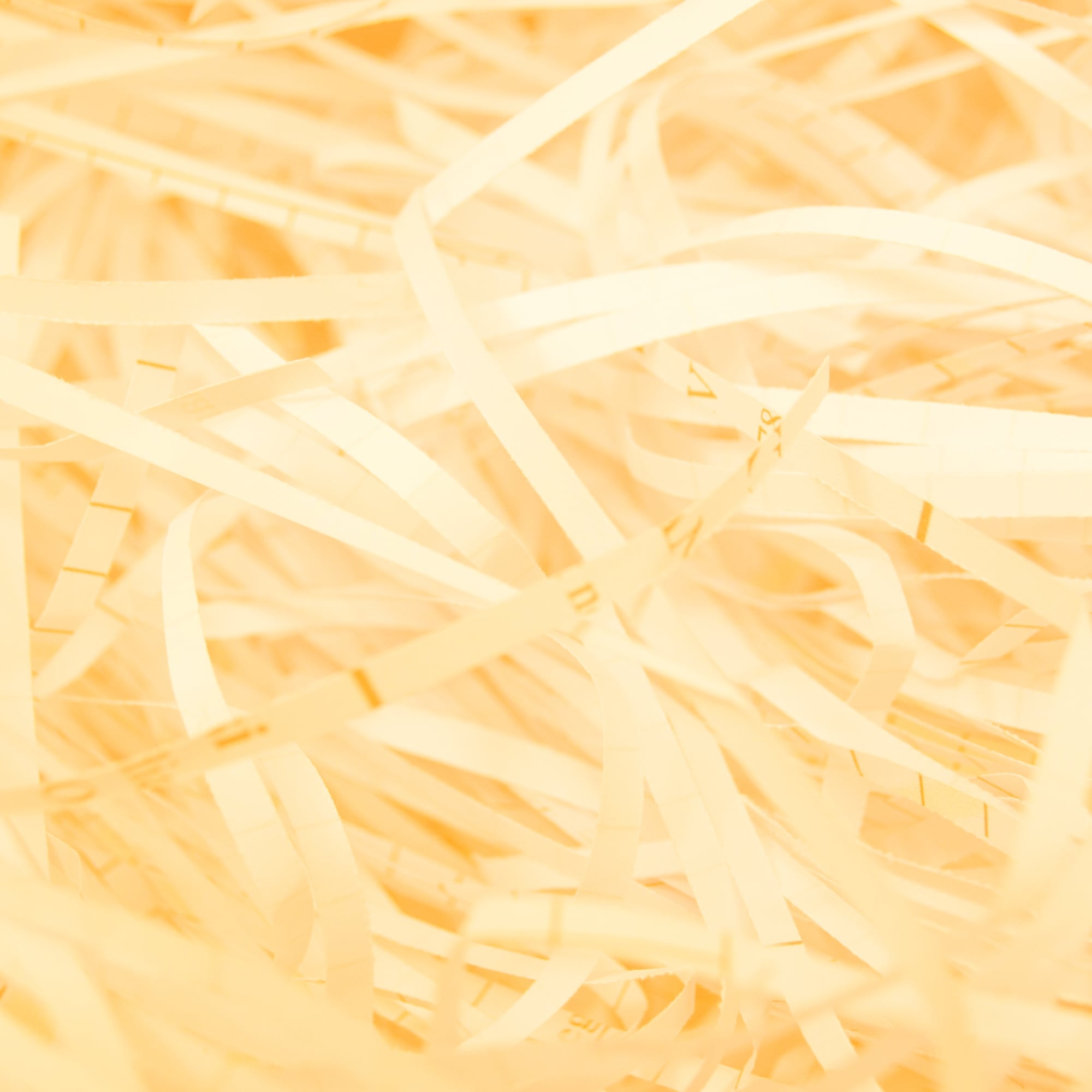 close up shredded paper strips texture cream toned background