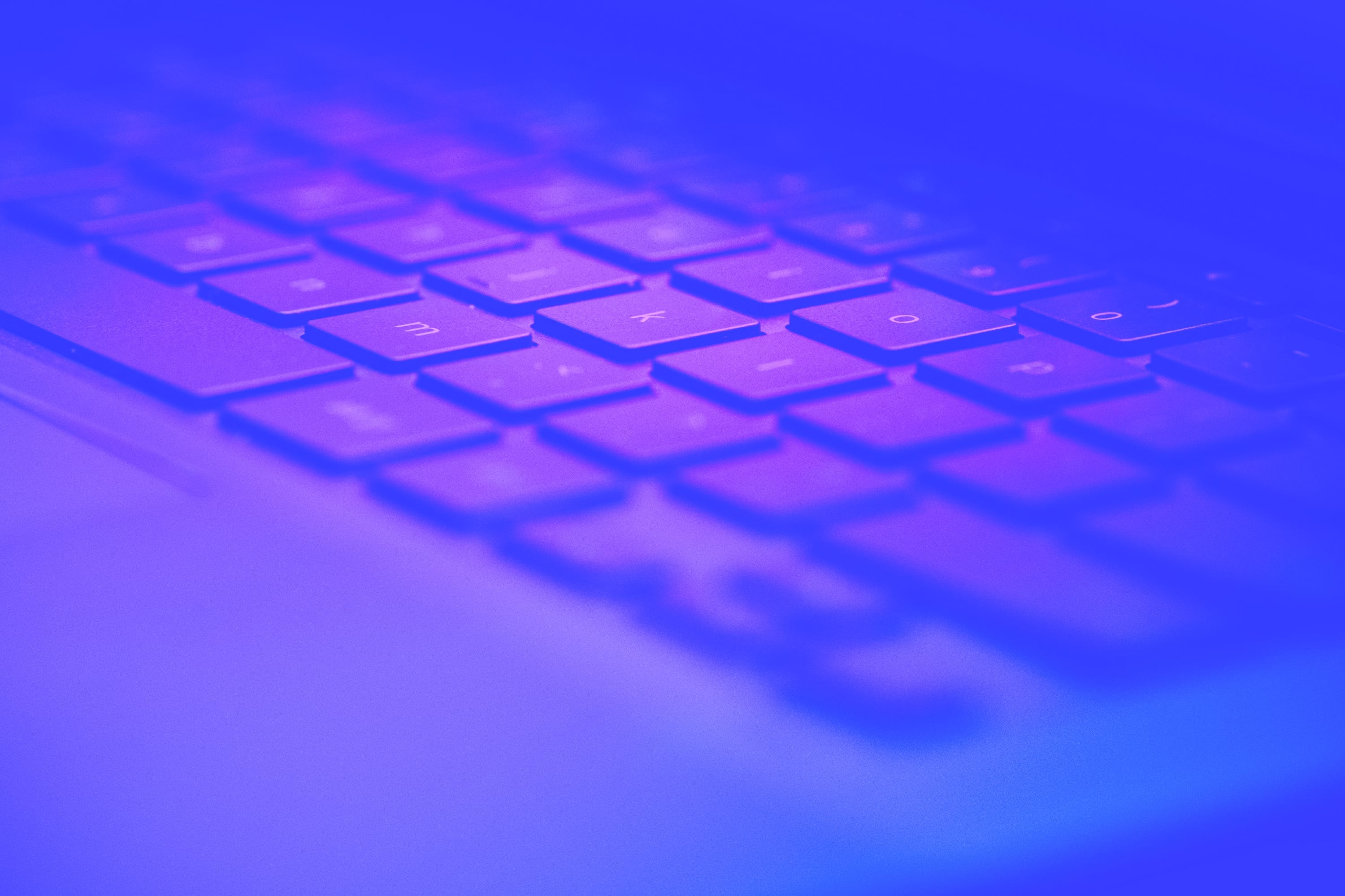 close up of laptop keyboard at angle blue purple toned