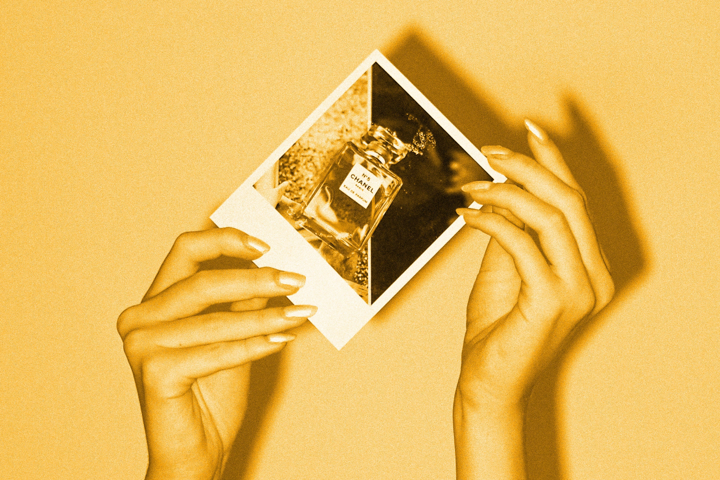 hands holding polaroid photo of chanel perfume bottle golden amber toned