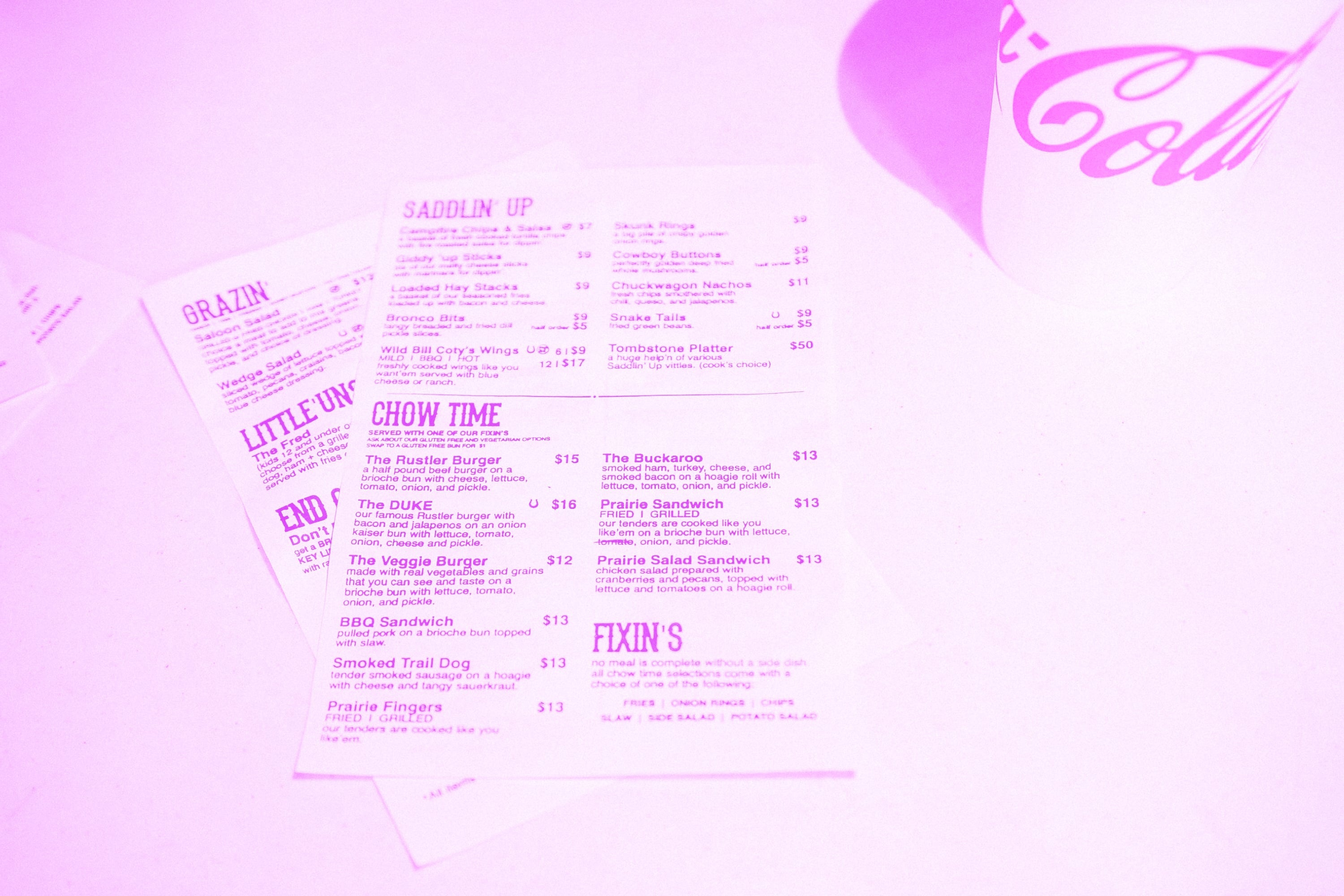american diner paper menus spread out on table with coca cola cup pink purple
