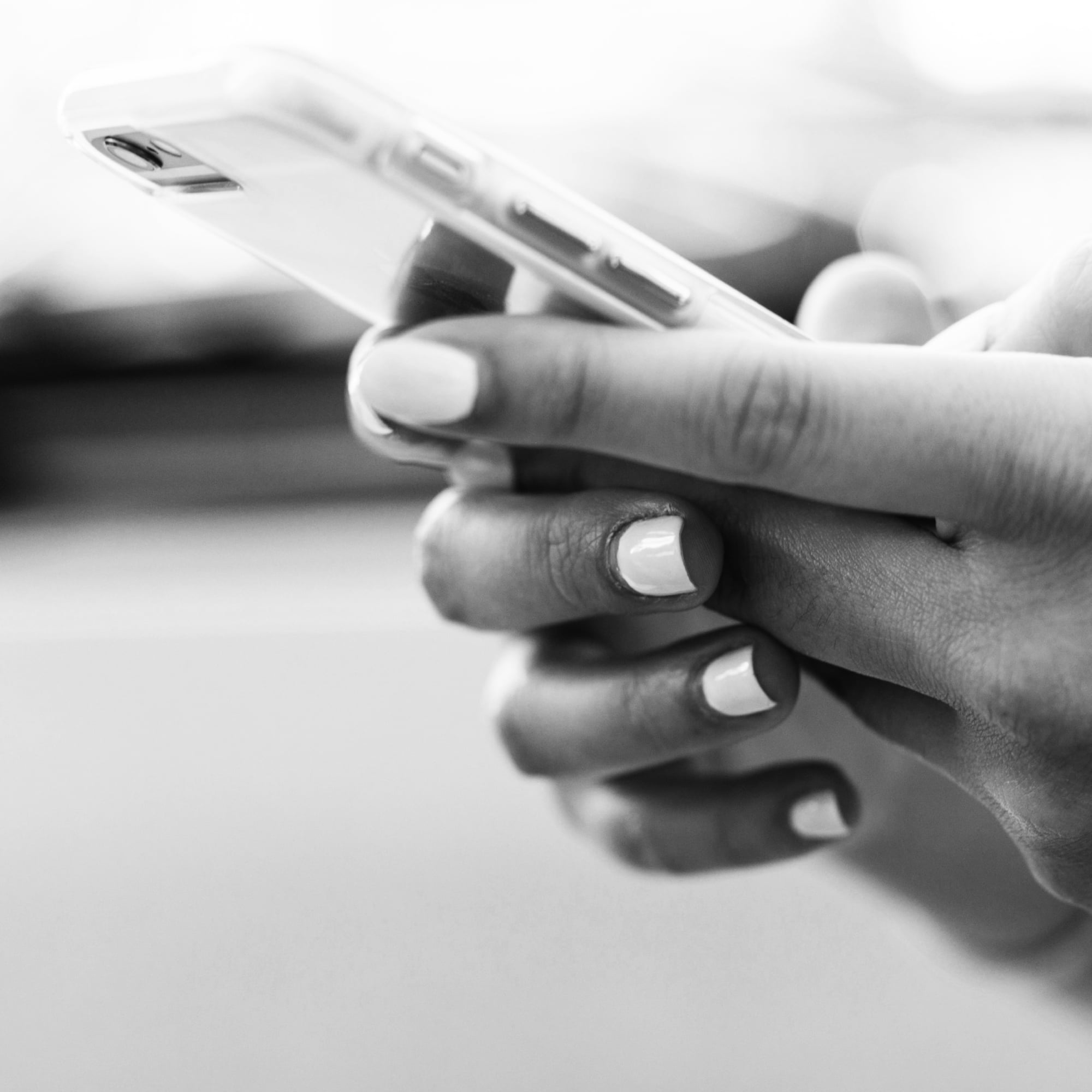close up of hands holding smartphone black and white manicured nails