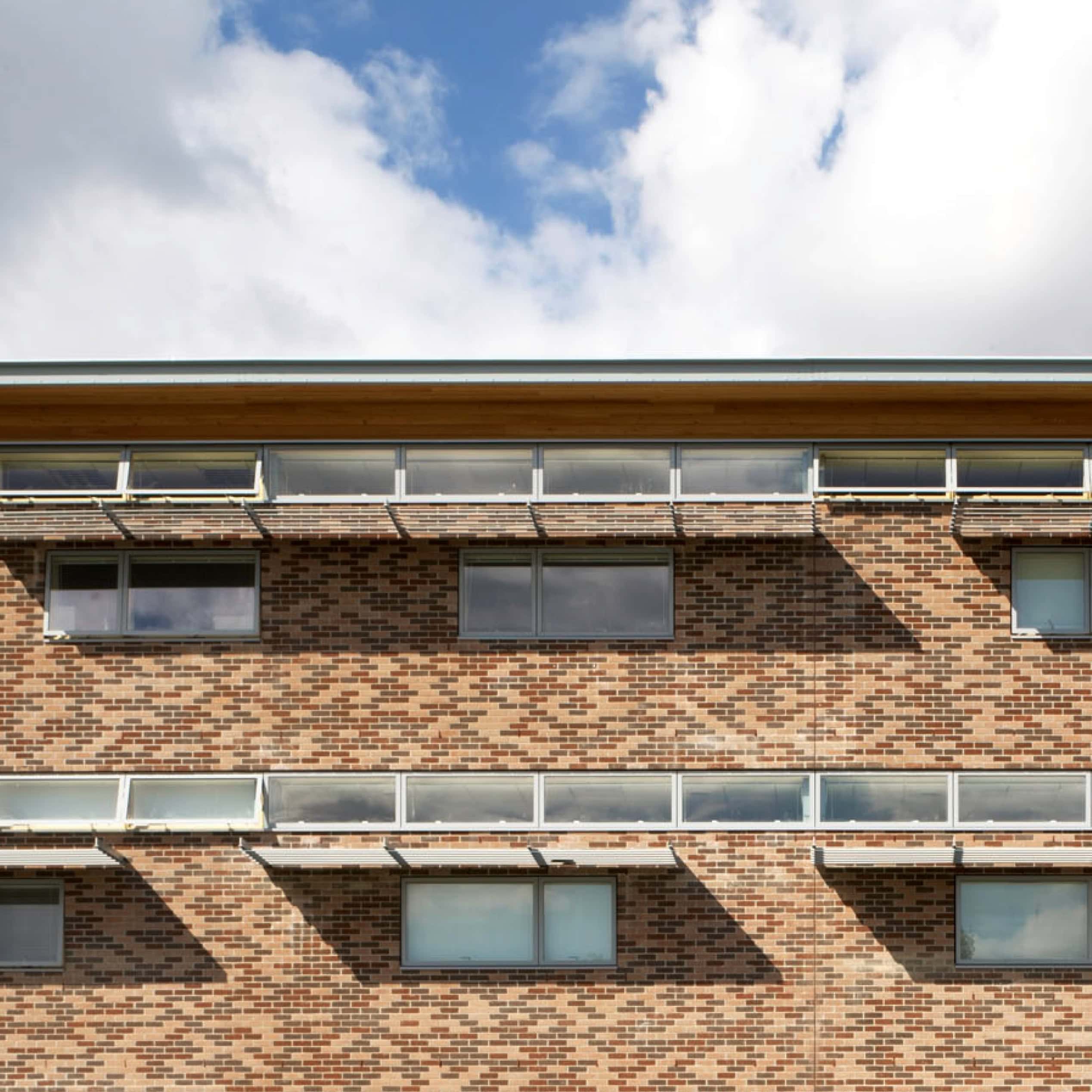 Brick building facade with horizontal strip windows beneath blue sky