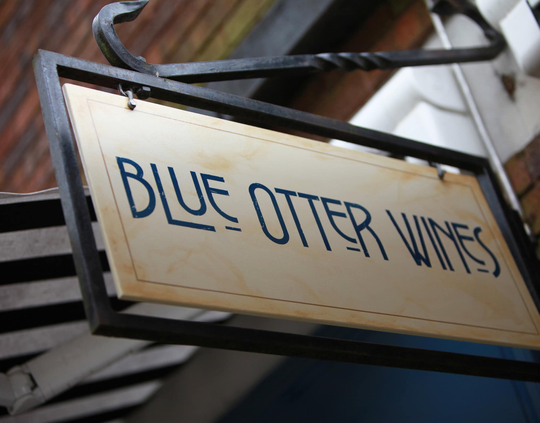 Hanging exterior sign for Blue Otter Wines on a metal bracket