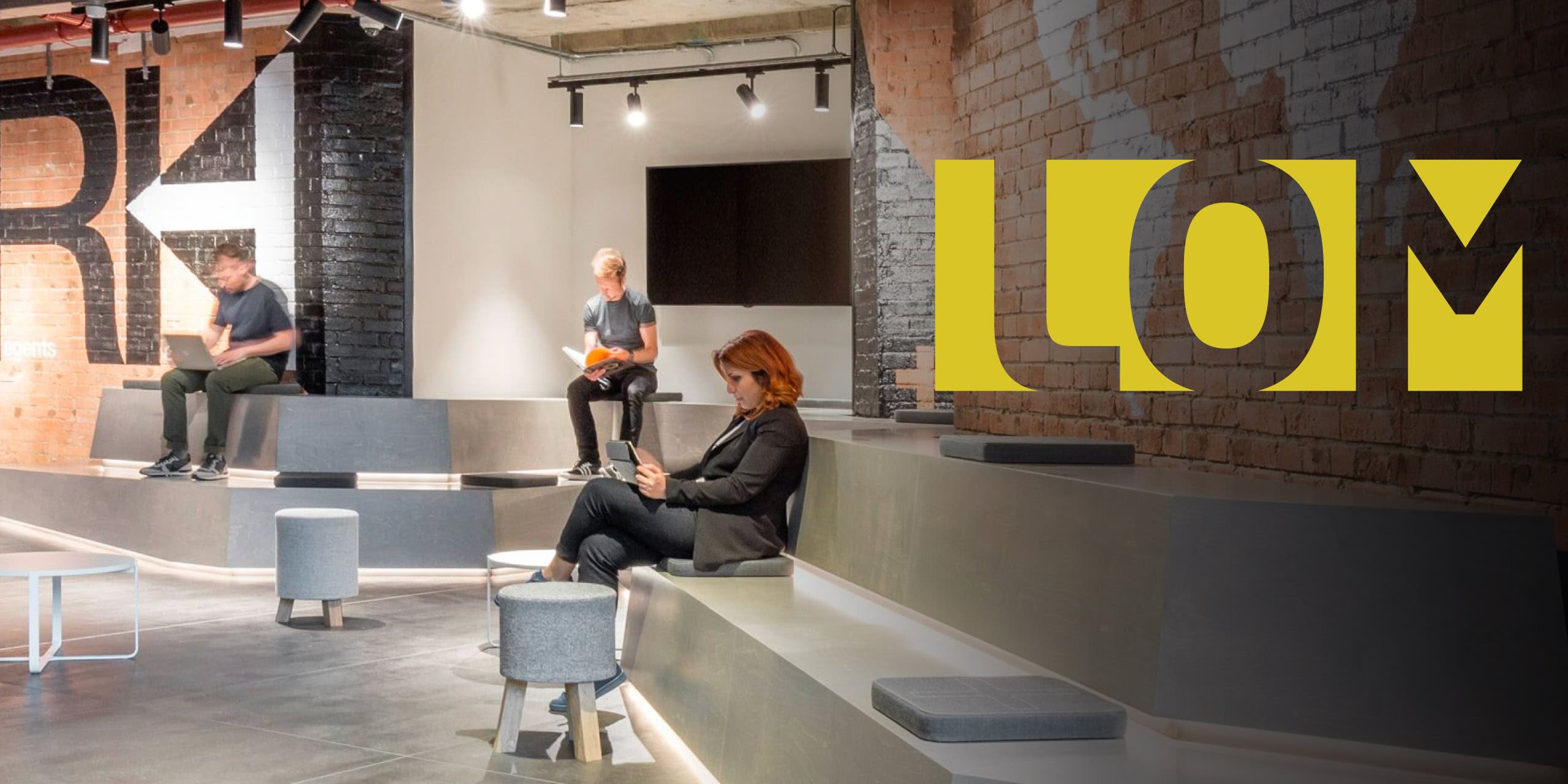 People working in studio lounge with tiered seating overlayed by a yellow LOM logo