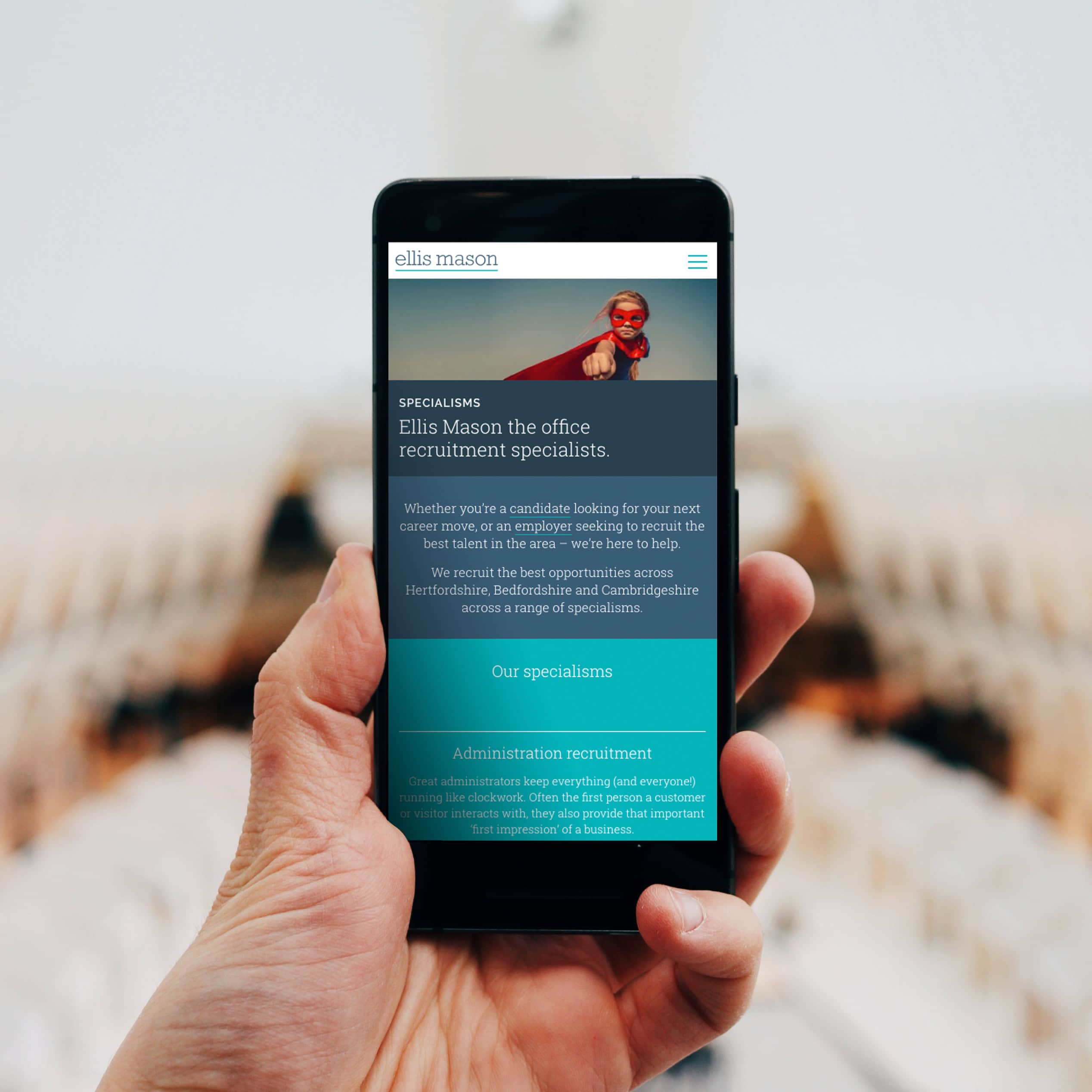Hand holding a smartphone displaying the Ellis Mason recruitment website homepage