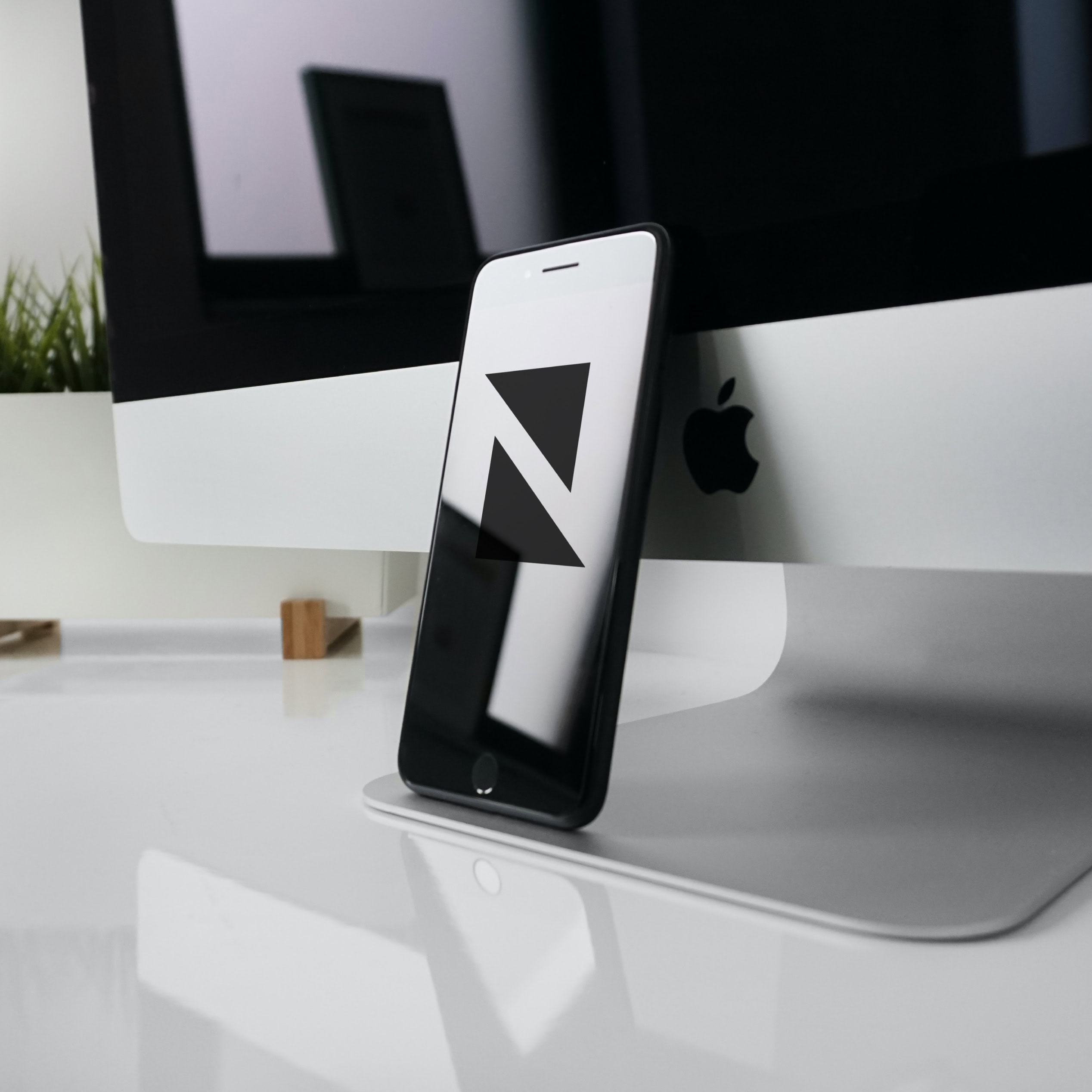 Newall Consulting logo shown on a mobile phone beside an iMac
