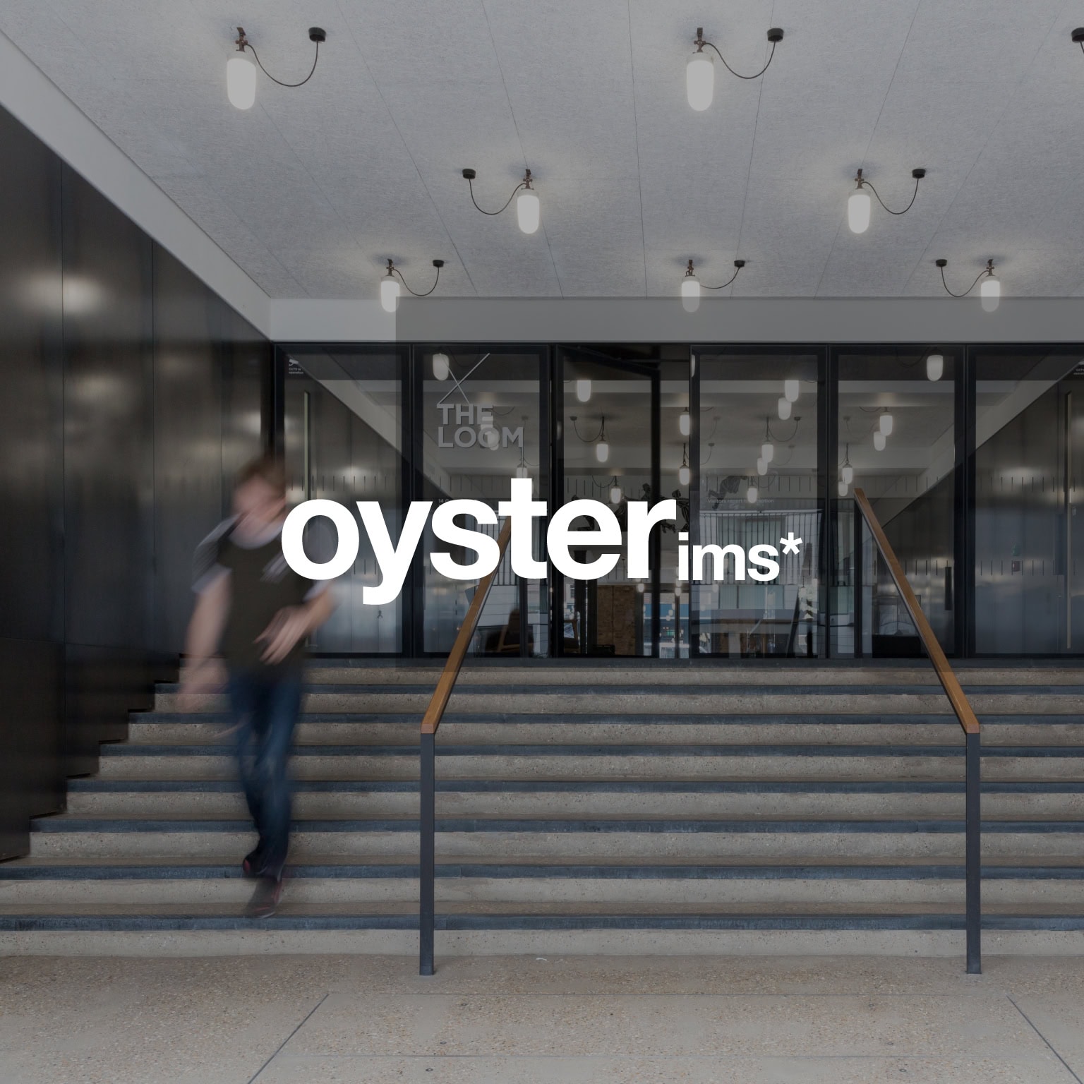 Oyster IMS logo over the entrance steps of a modern office building with glass doors and ceiling lights.